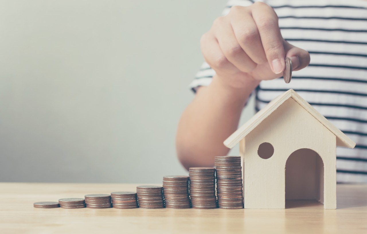 Průvodce refinancováním - naskládané mince vedle dřevěného baráčku